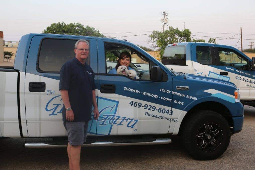 A man and woman standing in front of a white truck.