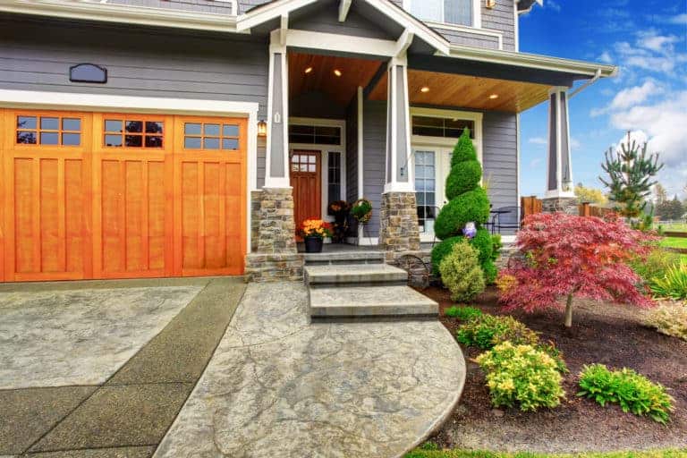 A home with an orange garage door and steps that exudes curb appeal.