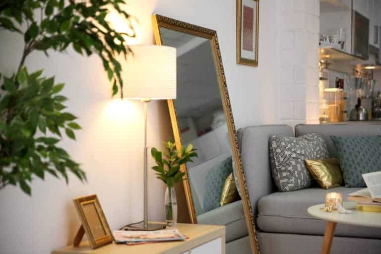 A living room with a couch adorned with decorative pillows and a stylish mirror hung on the wall.