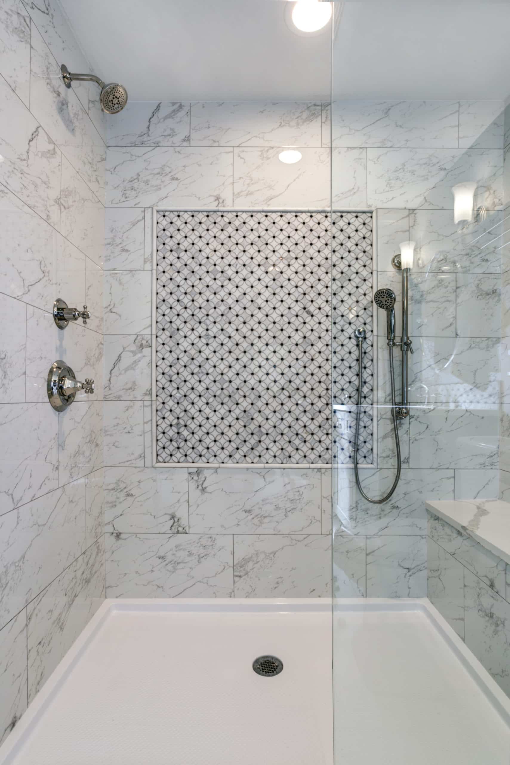 A walk-in shower with a marble shower and glass shower door.