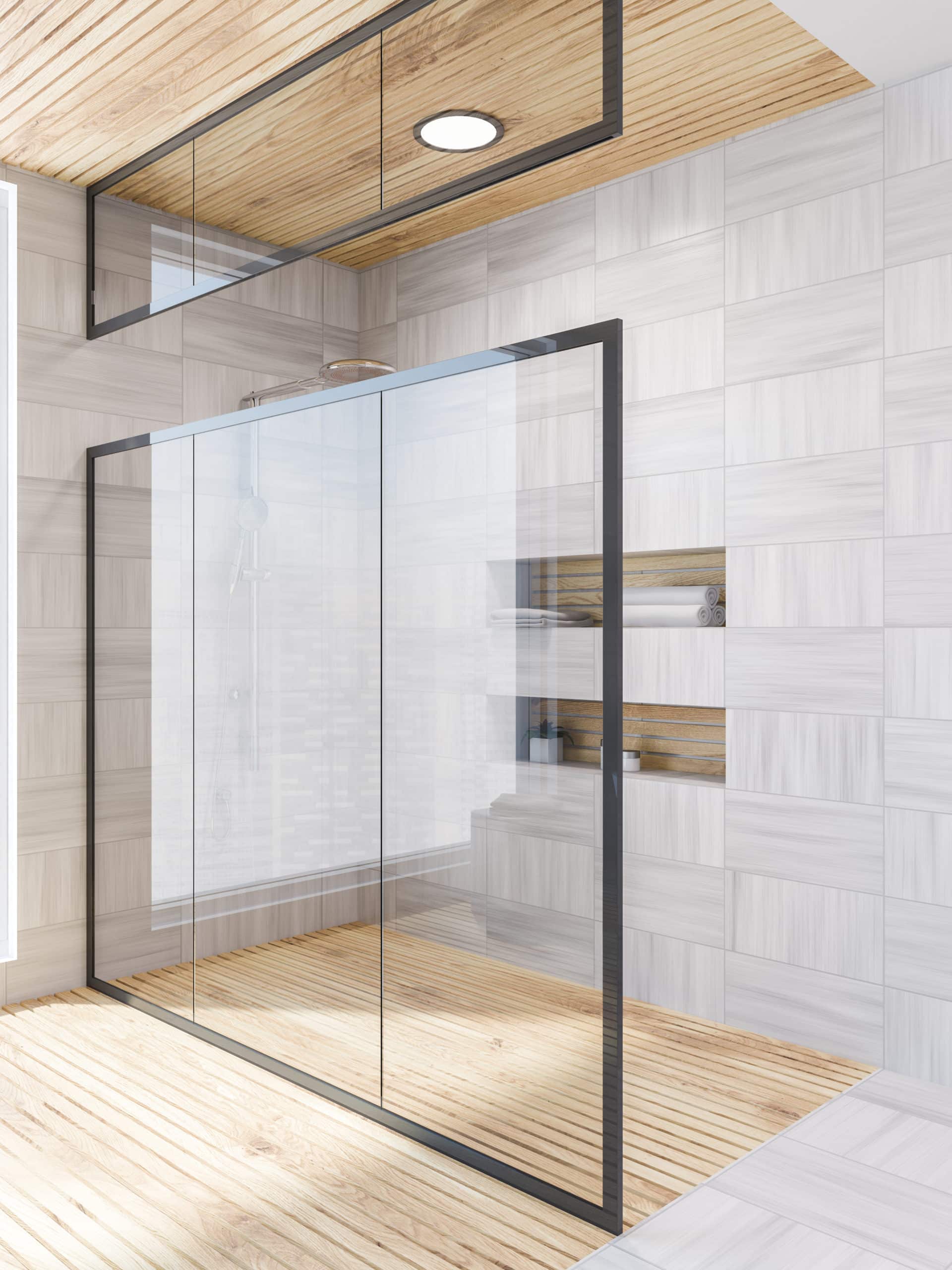 A bathroom with a wooden floors and a walk-in shower featuring a glass door.