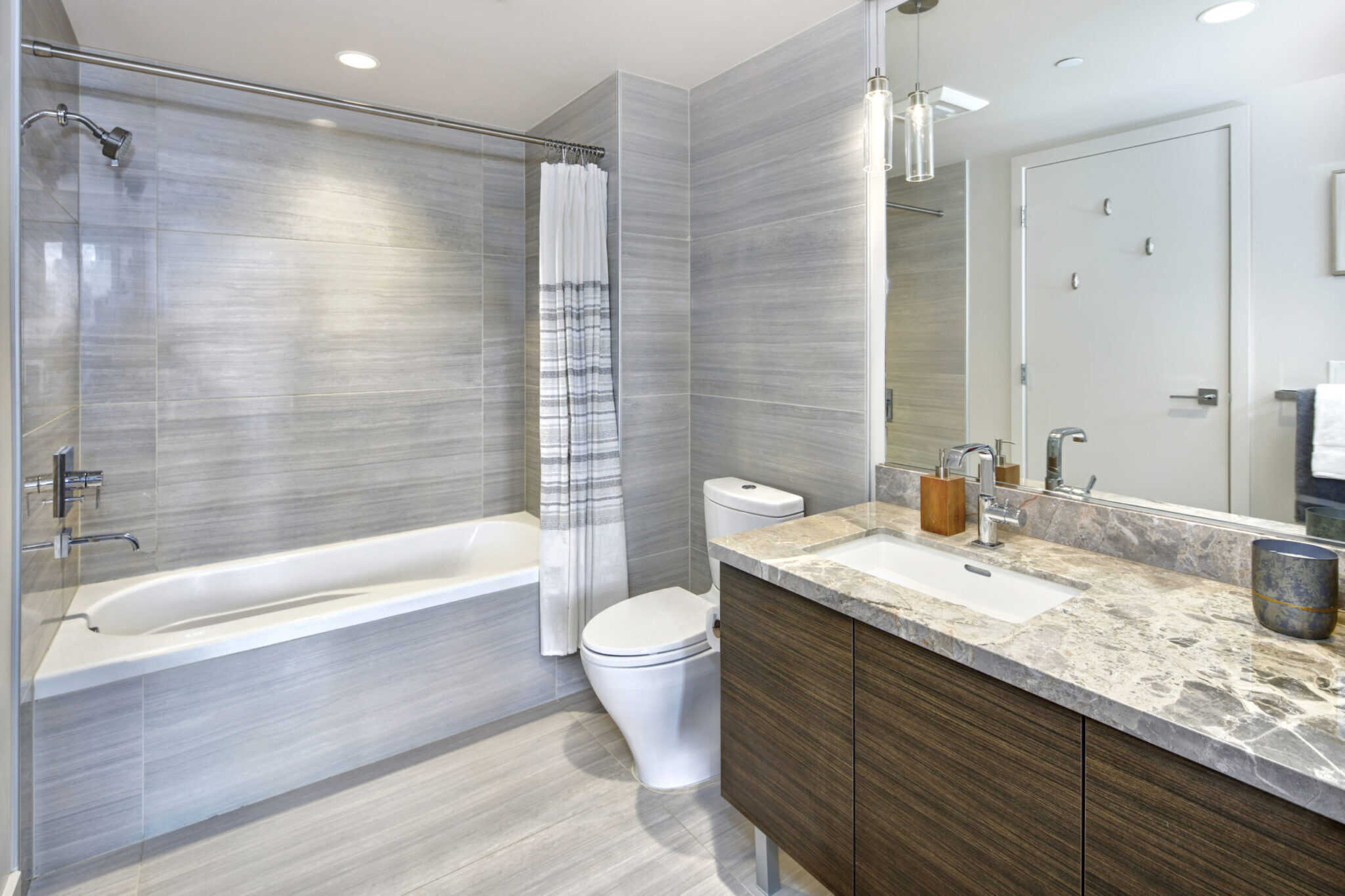 A bathroom with a bathtub, sink and mirror. (Keywords: bathtub)