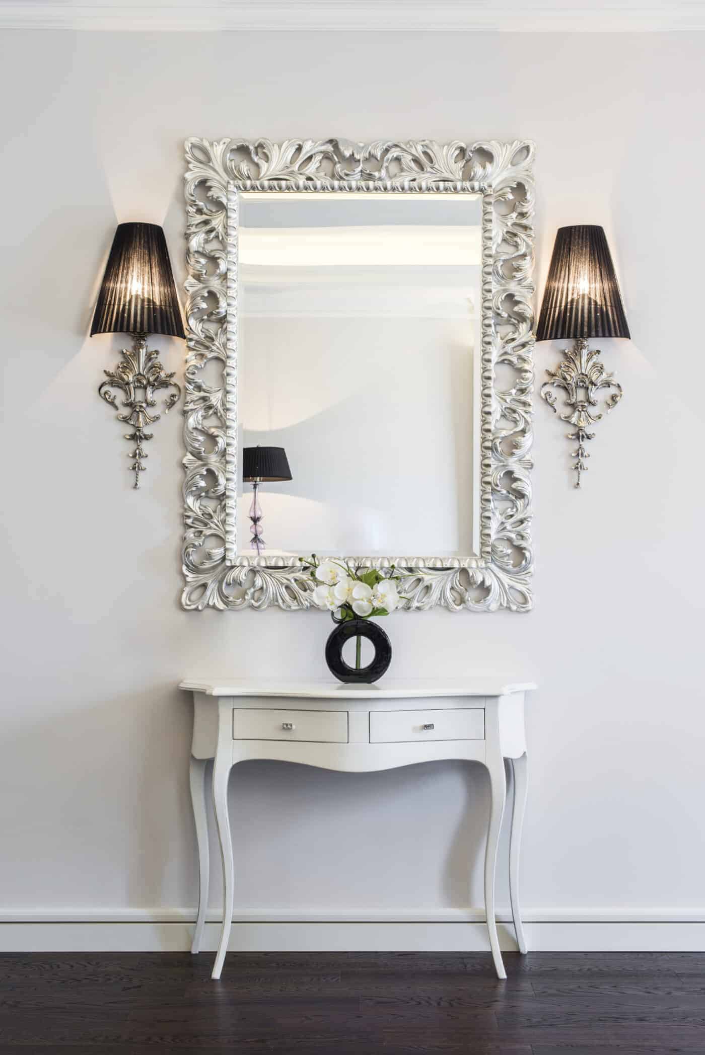 A stunning mirror hangs on the wall next to a console table.